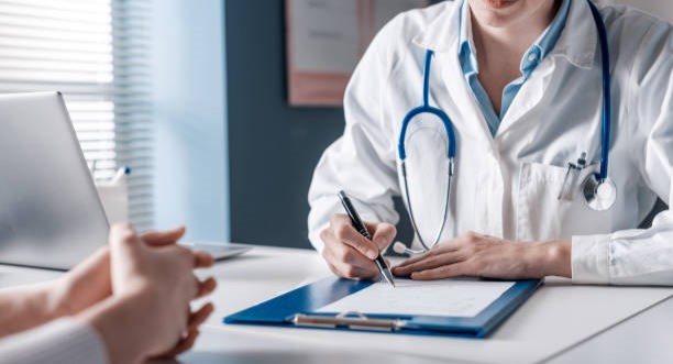 Doctor sitting at desk and writing a prescription for her patient